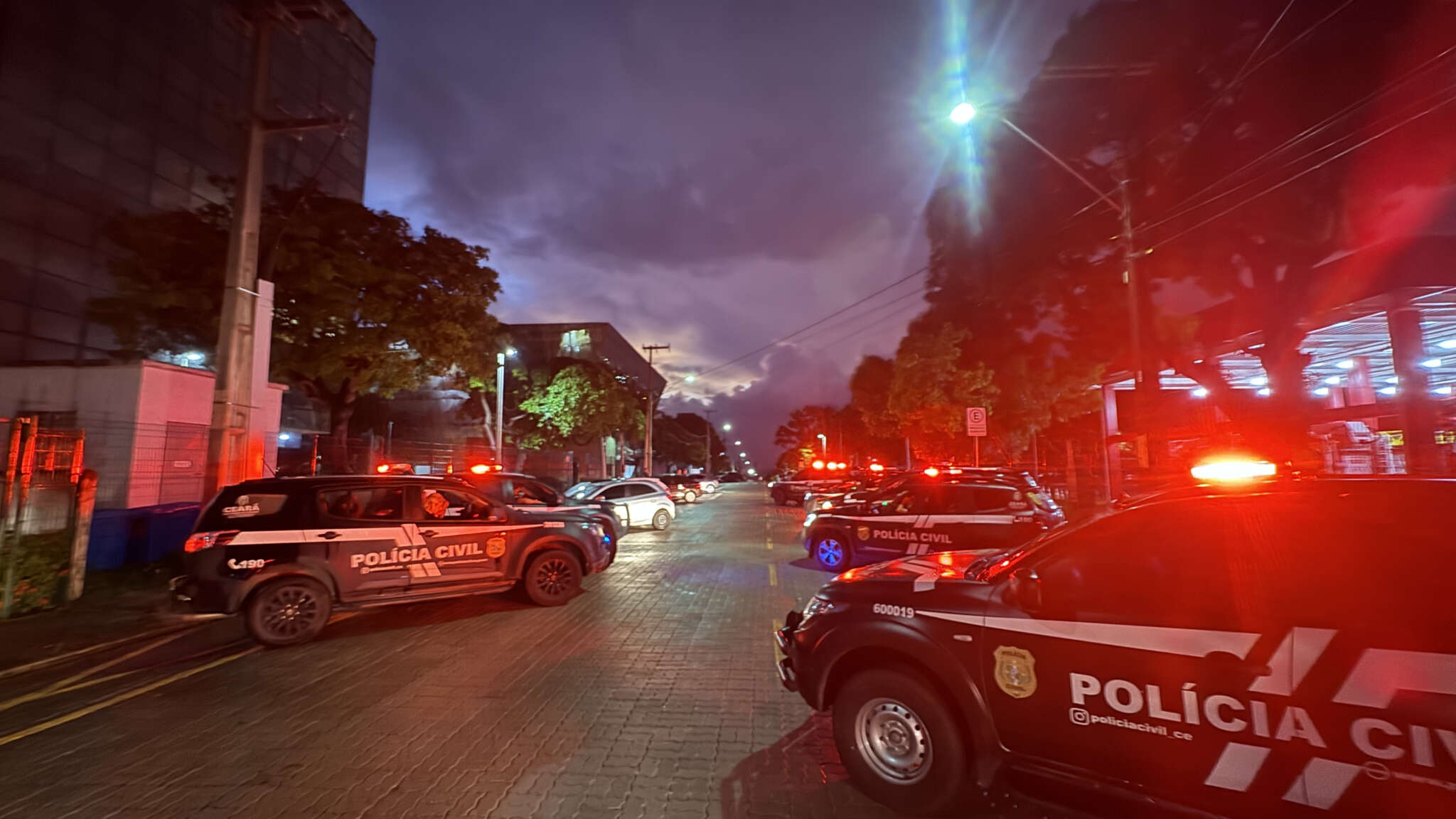 Viaturas da Polícia Civil com sirenes acesas durante operação que bloqueou bens de luxo ligados ao tráfico em São Paulo.