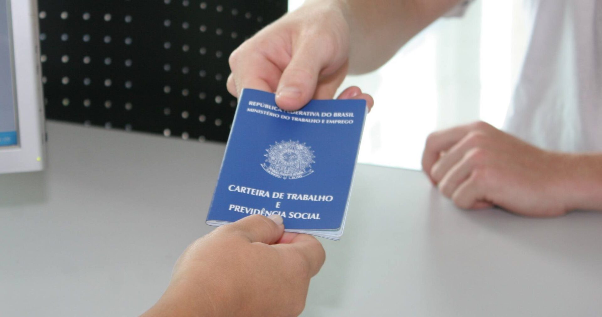 Pessoa entrega carteira de trabalho durante contratação formal, representando a geração de emprego no Espírito Santo em setembro.