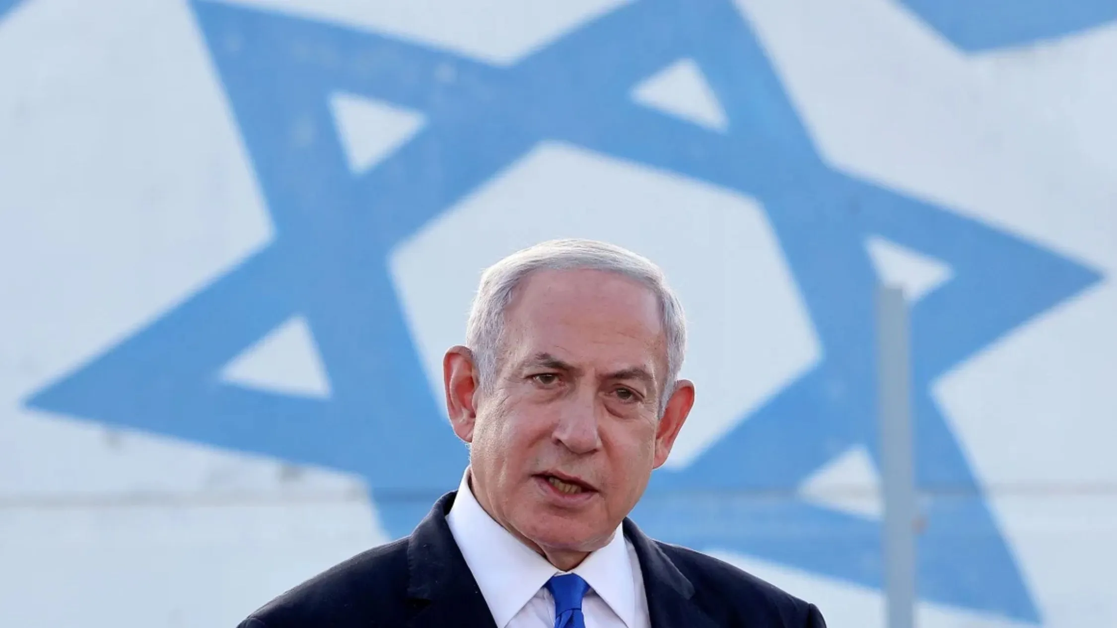 Benjamin Netanyahu fala à imprensa em frente à bandeira de Israel após ordenar novos ataques aéreos contra a Faixa de Gaza
