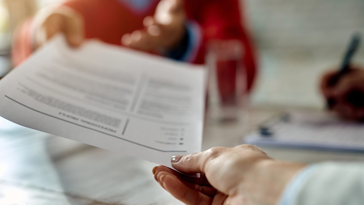 Pessoa entrega currículo durante entrevista de emprego, representando o apagão de mão de obra qualificada na Bahia.