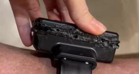 Tornozeleira eletrônica danificada, com a superfície queimada e deformada por calor intenso, sendo segurada pela mão de uma pessoa.