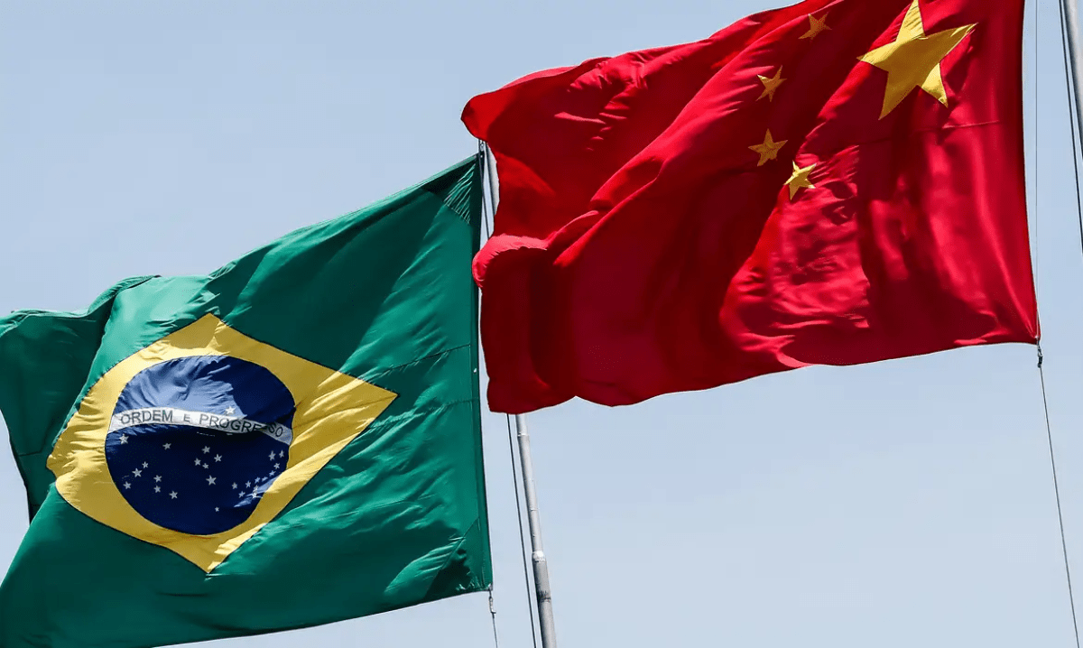 Bandeiras do Brasil e da China hasteadas lado a lado em um dia ensolarado, simbolizando cooperação diplomática e laços econômicos entre os dois países.