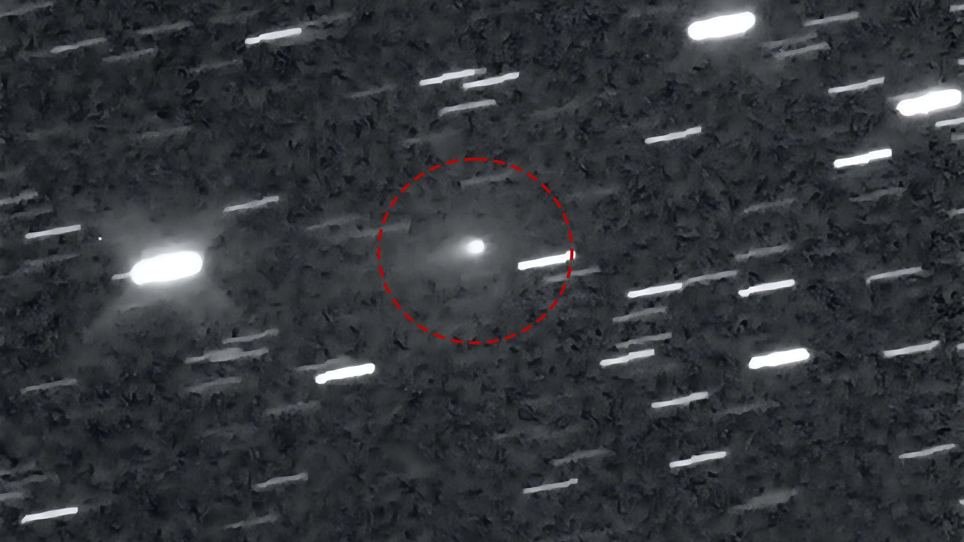 Imagem astronômica mostra cometa 3I/ATLAS destacado por círculo vermelho no centro com estrelas em segundo plano