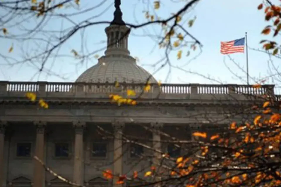 Cúpula do Capitólio dos Estados Unidos com bandeira americana ao fundo durante o outono, simbolizando o fim do shutdown governamental.