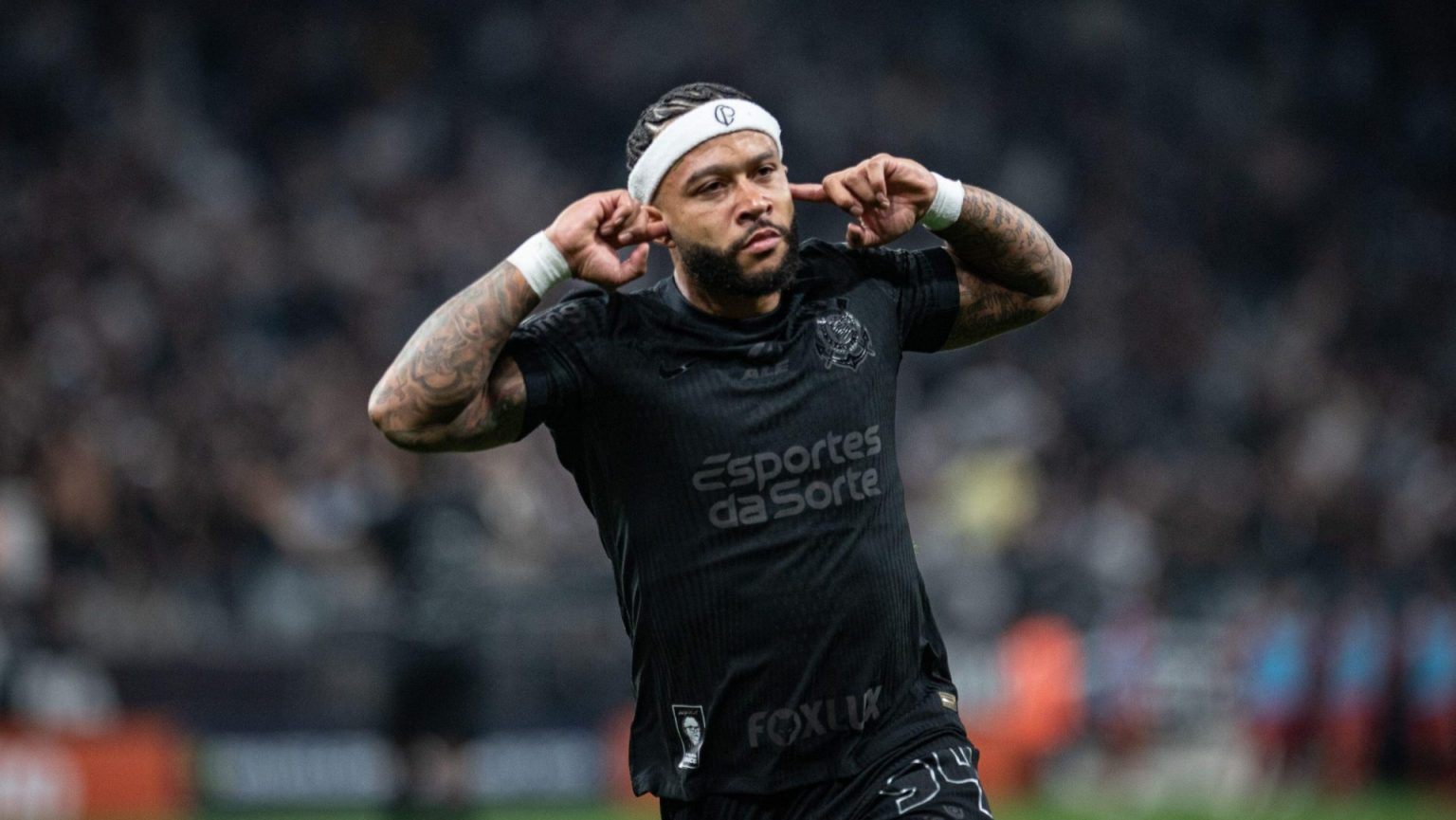 Jogador do Corinthians celebra gol com as mãos nos ouvidos durante partida contra o Grêmio pelo Campeonato Brasileiro.