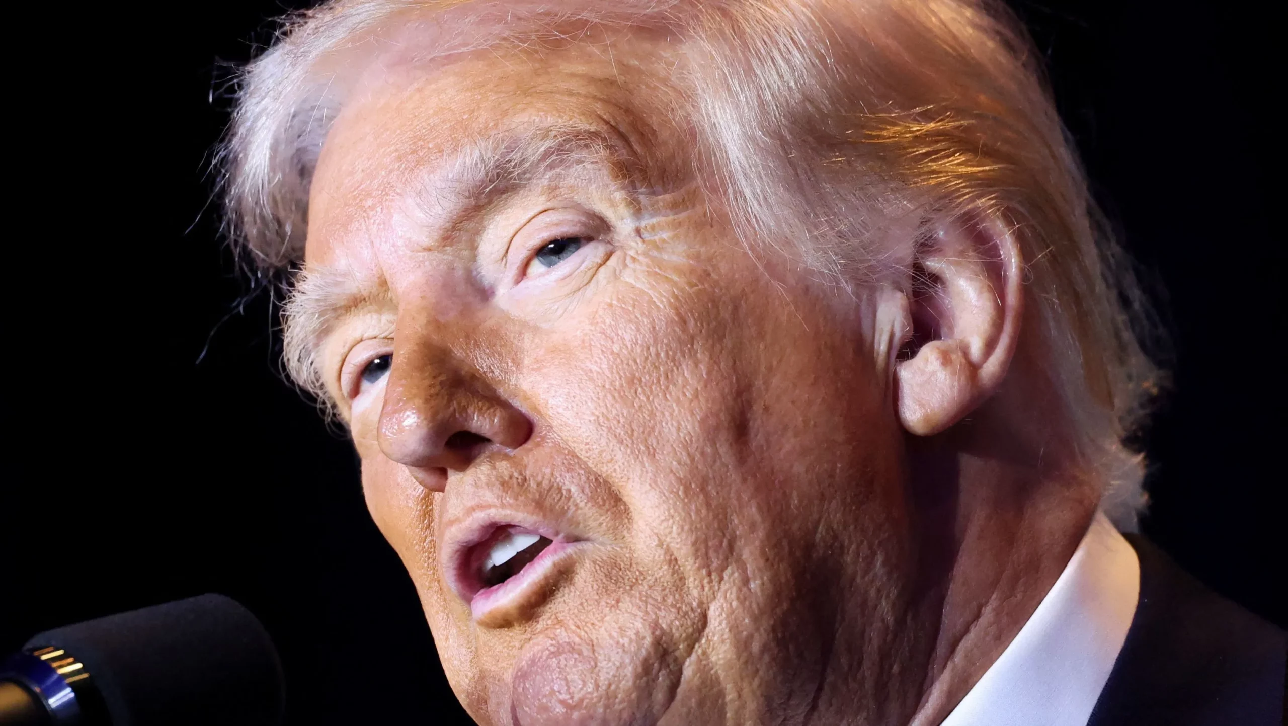 Donald Trump fala durante evento oficial em Washington, com iluminação lateral destacando o rosto do presidente norte-americano durante pronunciamento recente à imprensa.