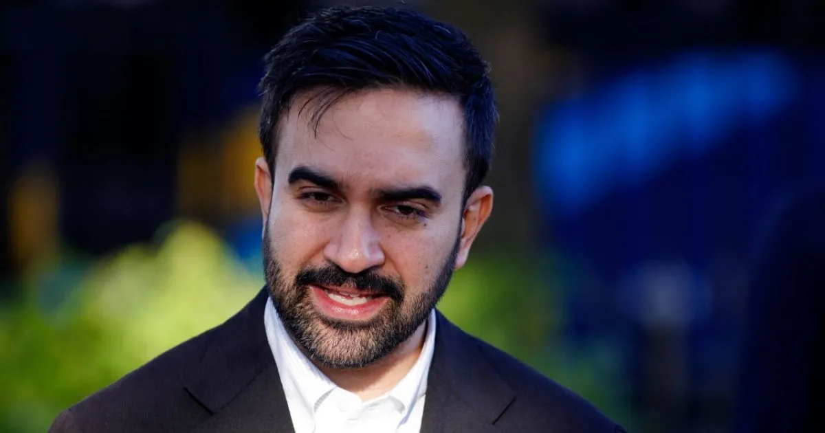 Homem de barba e cabelos curtos escuros, usando paletó preto e camisa branca, fala em ambiente externo com fundo desfocado.