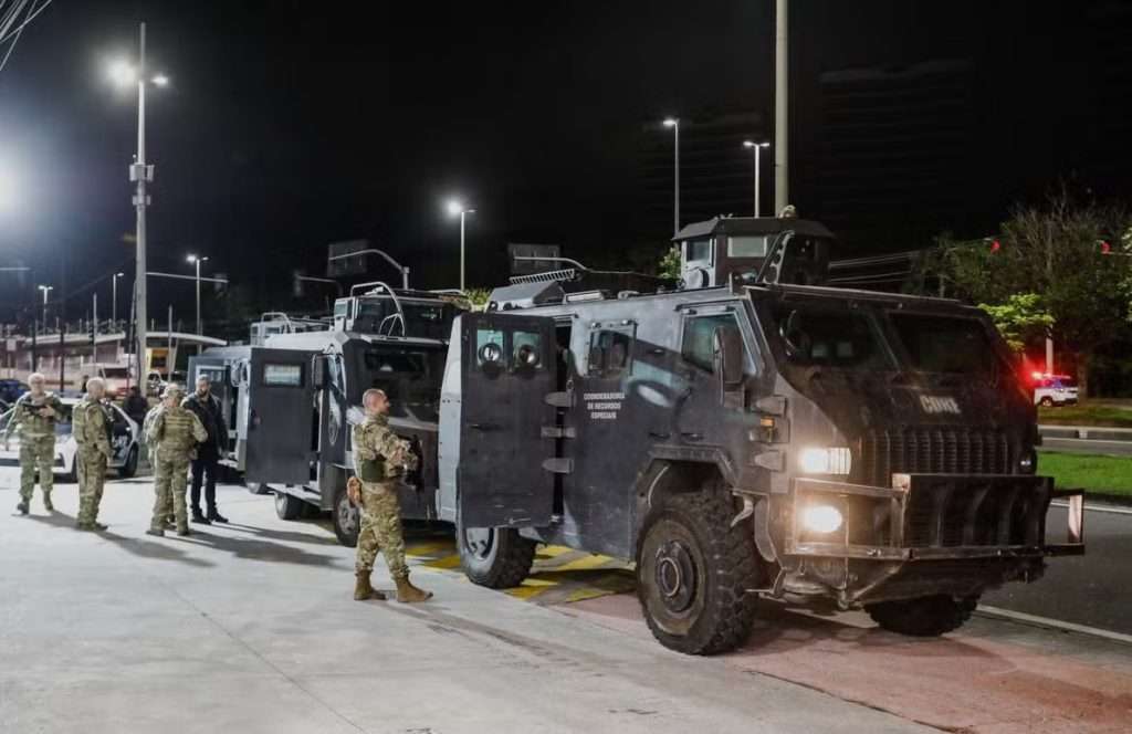 Policiais e veículos blindados durante megaoperação no Rio de Janeiro, realizada à noite, em ação de combate ao crime organizado.