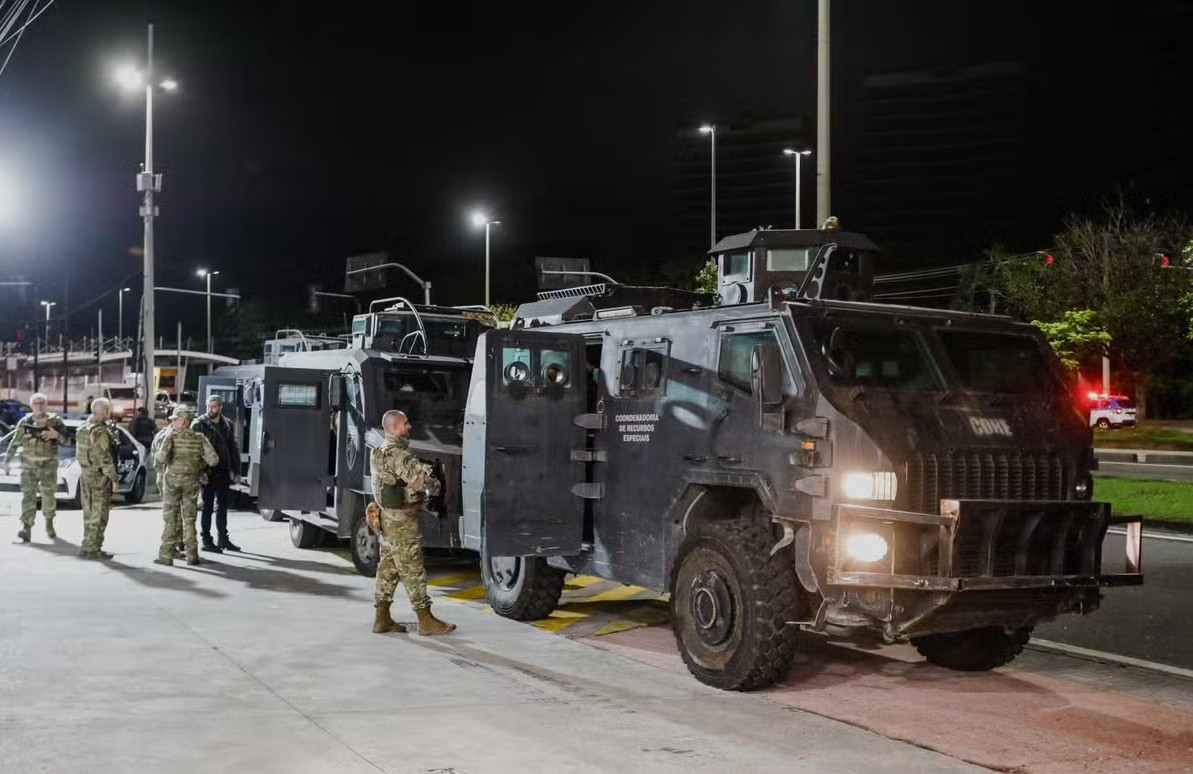 Policiais e veículos blindados durante megaoperação no Rio de Janeiro, realizada à noite, em ação de combate ao crime organizado.