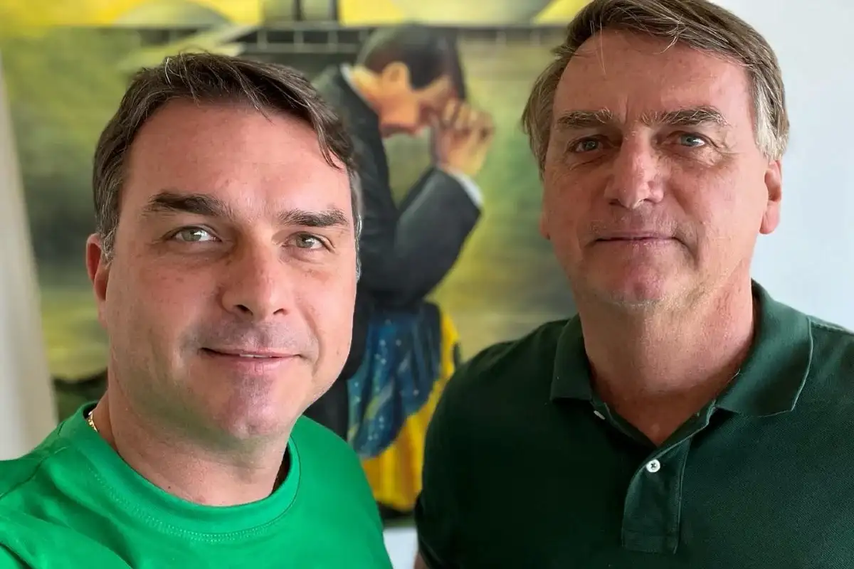 Flávio Bolsonaro tira selfie ao lado de seu pai, Jair Bolsonaro, ambos vestindo verde.