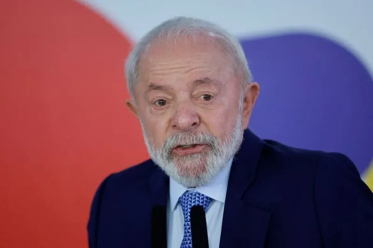 O Presidente Luiz Inácio Lula da Silva discursa em púlpito, com um fundo decorado por círculos coloridos, em um pronunciamento oficial.