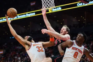 Jogadores de basquete de New York Knicks e Toronto Raptors disputam a bola em partida da NBA Cup.