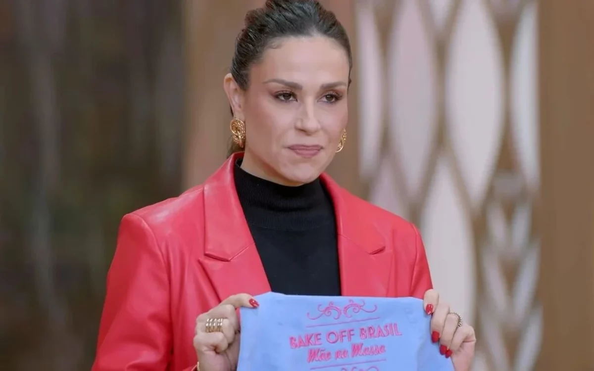 A apresentadora do reality show de culinária Bake Off Brasil, exibido no SBT aos sábados, segura um avental, com expressão séria ou decepcionada, refletindo a crise de audiência.