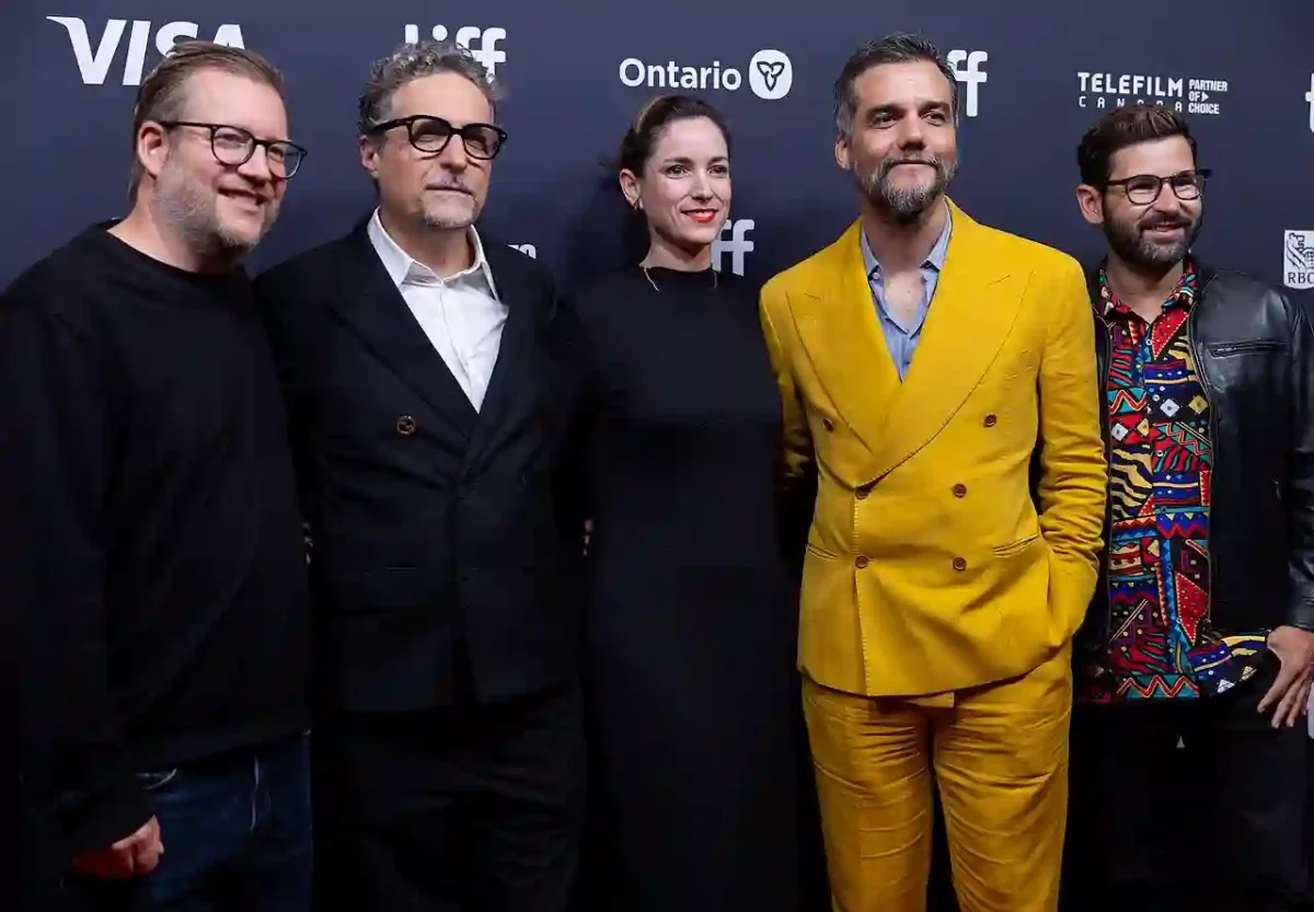 Wagner Moura e elenco do filme O Agente Secreto posam em tapete vermelho de festival internacional com sorrisos e trajes formais.